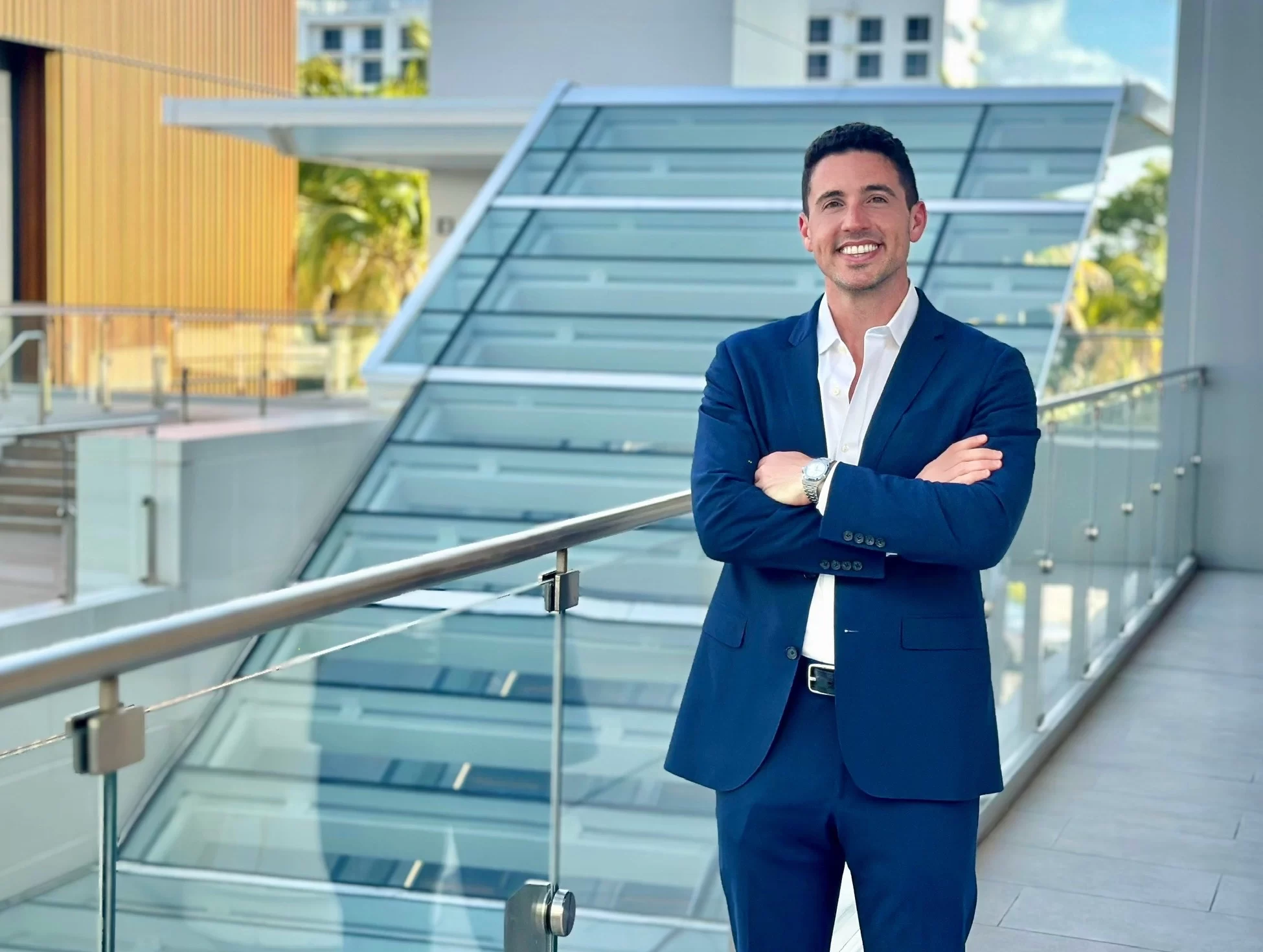 Brandon Pomeranz in a sharp navy suit representing Unclaimed Digital, standing confidently on a luxury terrace with a modern design